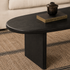Close-up of black ash wood coffee table showing natural wood grain, rounded tabletop edge and solid panel leg.