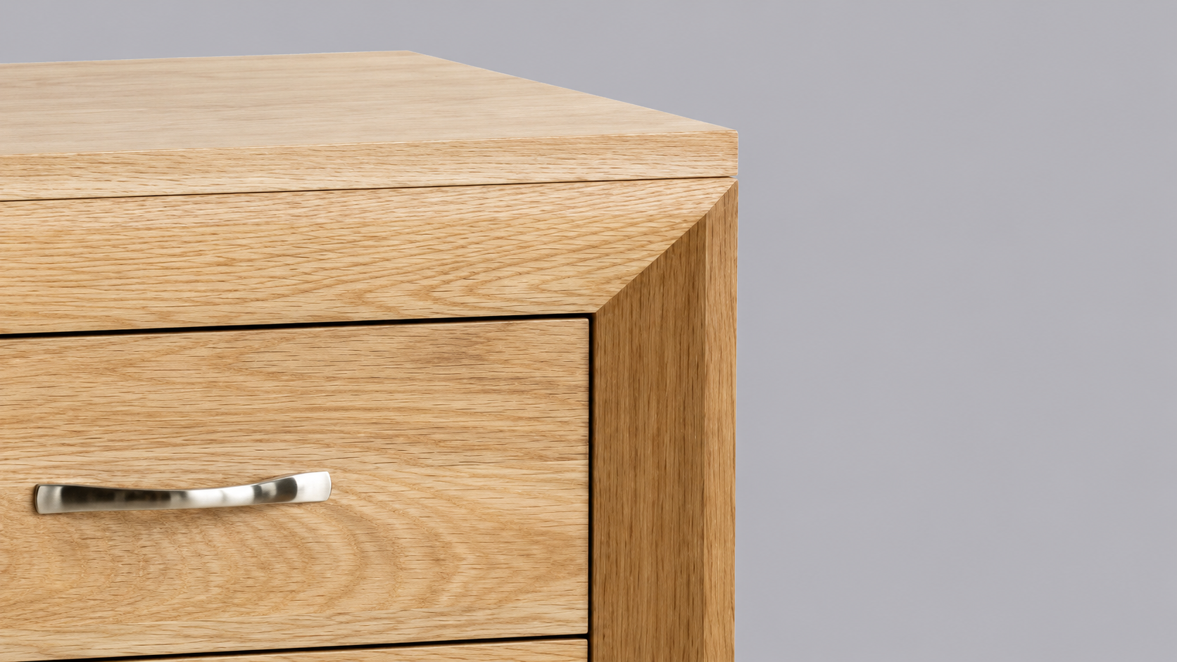 Close-up of the Chamfer Natural and Grey-Wash Oak Furniture Collection showing clean chamfered edges, natural oak grain, and a sleek silver handle detail