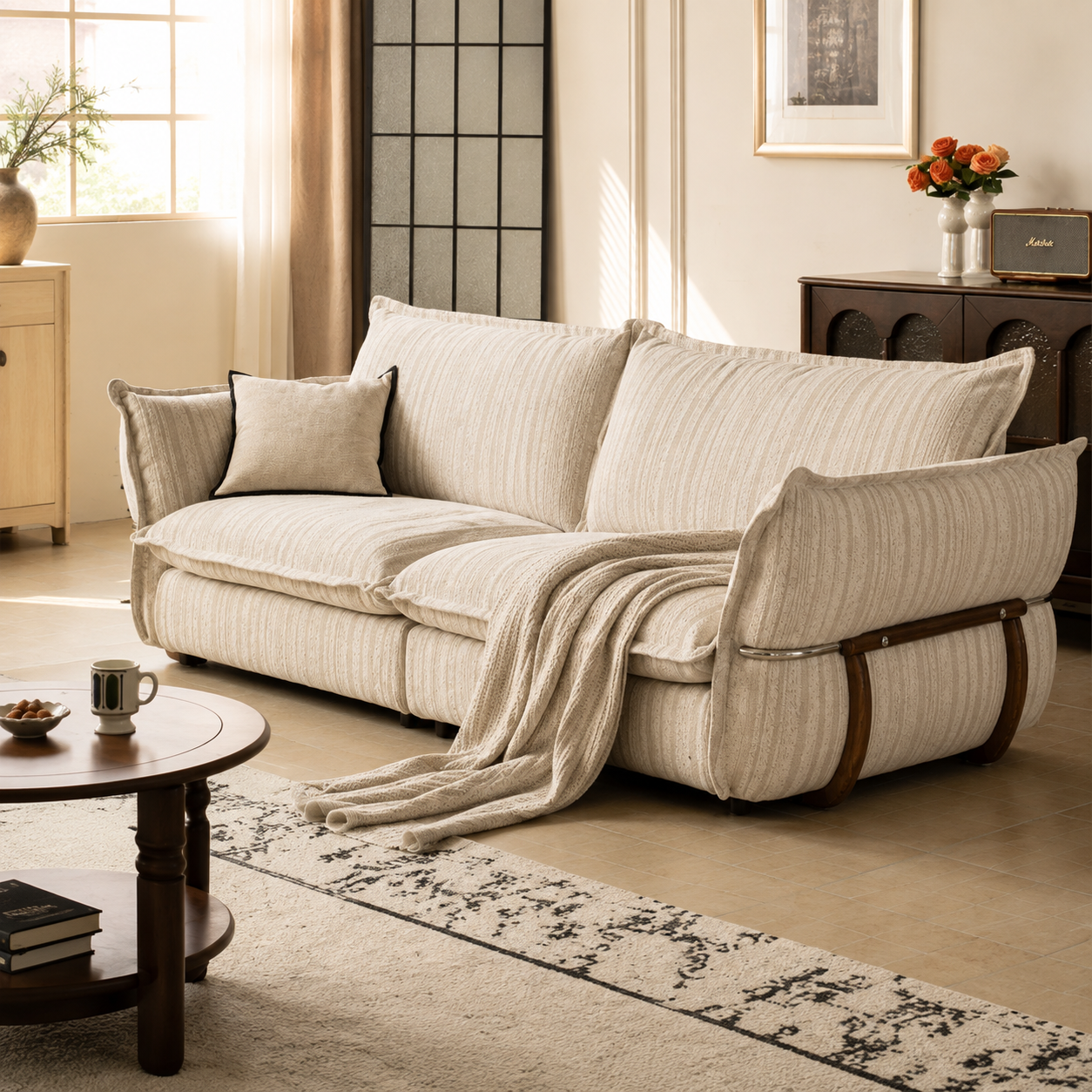 Detailed view of the cream striped sofa arm with soft upholstery, curved wooden frame and polished metal rail.