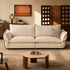 Cream striped fabric sofa with oversized cushions, curved wooden side frames and metal accent rails in a warm living room.