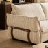 Close-up of the cream striped sofa side showing padded upholstery, curved timber supports and metal rail detailing.