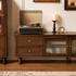 Close-up of the storage drawer on a dark wood TV unit with a brass knob and natural wood grain.