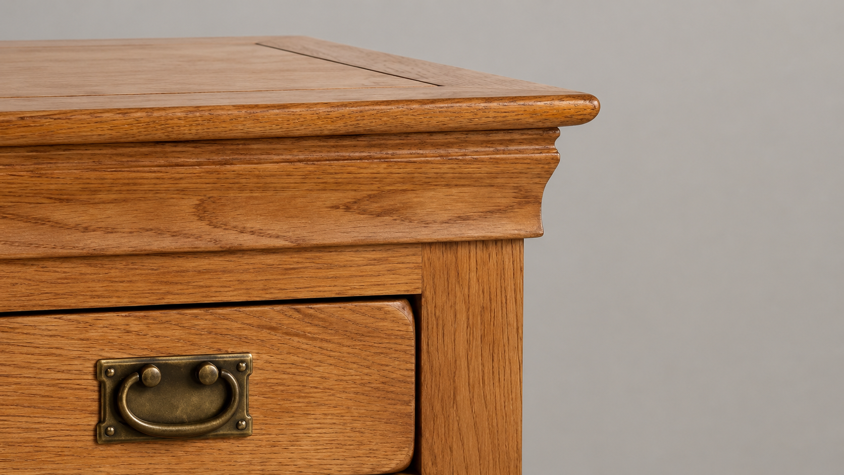 Close-up of the French Rustic Rustic Oak Furniture Collection showing warm rustic oak grain, decorative profile edging, and antique brass drawer handle detail
