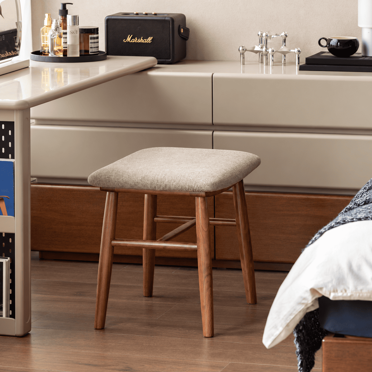 Natural solid walnut dressing stool with padded fabric seat in a warm bedroom vanity setting