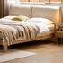 Natural oak bed frame with a cushioned cream headboard, combining modern comfort with timeless design.