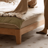 Solid oak bed frame with a cream upholstered headboard and minimalist contemporary design.