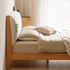 Light oak bed frame with a soft upholstered headboard and contemporary minimalist styling.