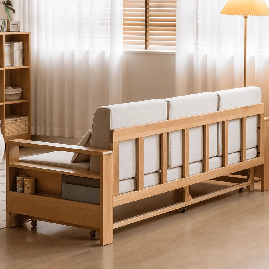 Natural oak sofa bed styled with matching pillows, side storage, and soft neutral décor