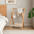 Naila natural solid beech folding coat rack styled beside bed in warm bedroom setting