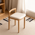 Nampa natural solid oak dressing stool with cream cushioned seat and rounded backrest in a warm bedroom setting