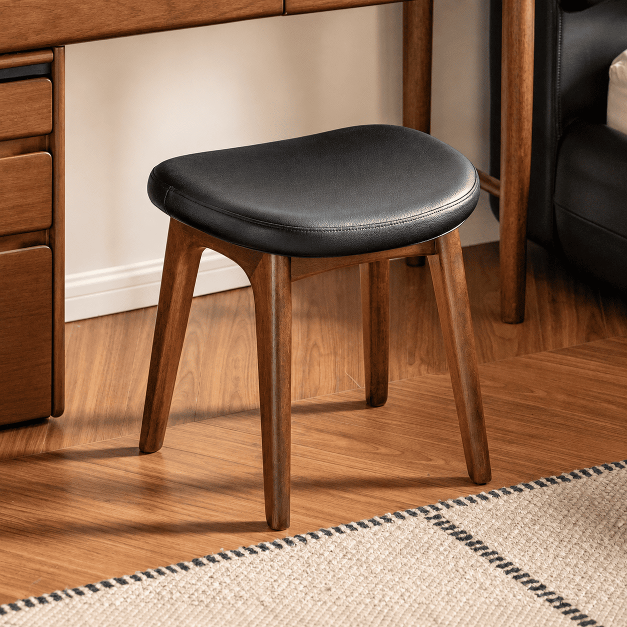 Norman natural solid walnut dressing stool with black upholstered seat styled under a wooden dressing table