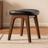 Norman solid walnut dressing stool with black cushioned seat and curved wooden frame