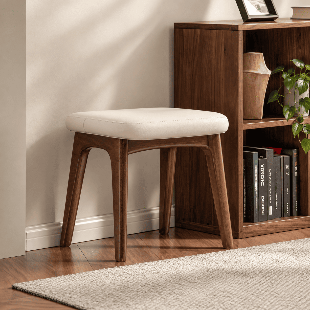 Norman natural solid walnut dressing stool with cream upholstered seat beside a wooden shelving unit