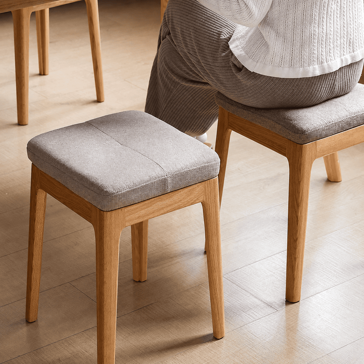 Set of three nesting oak stools with upholstered fabric seats and a space-saving design.