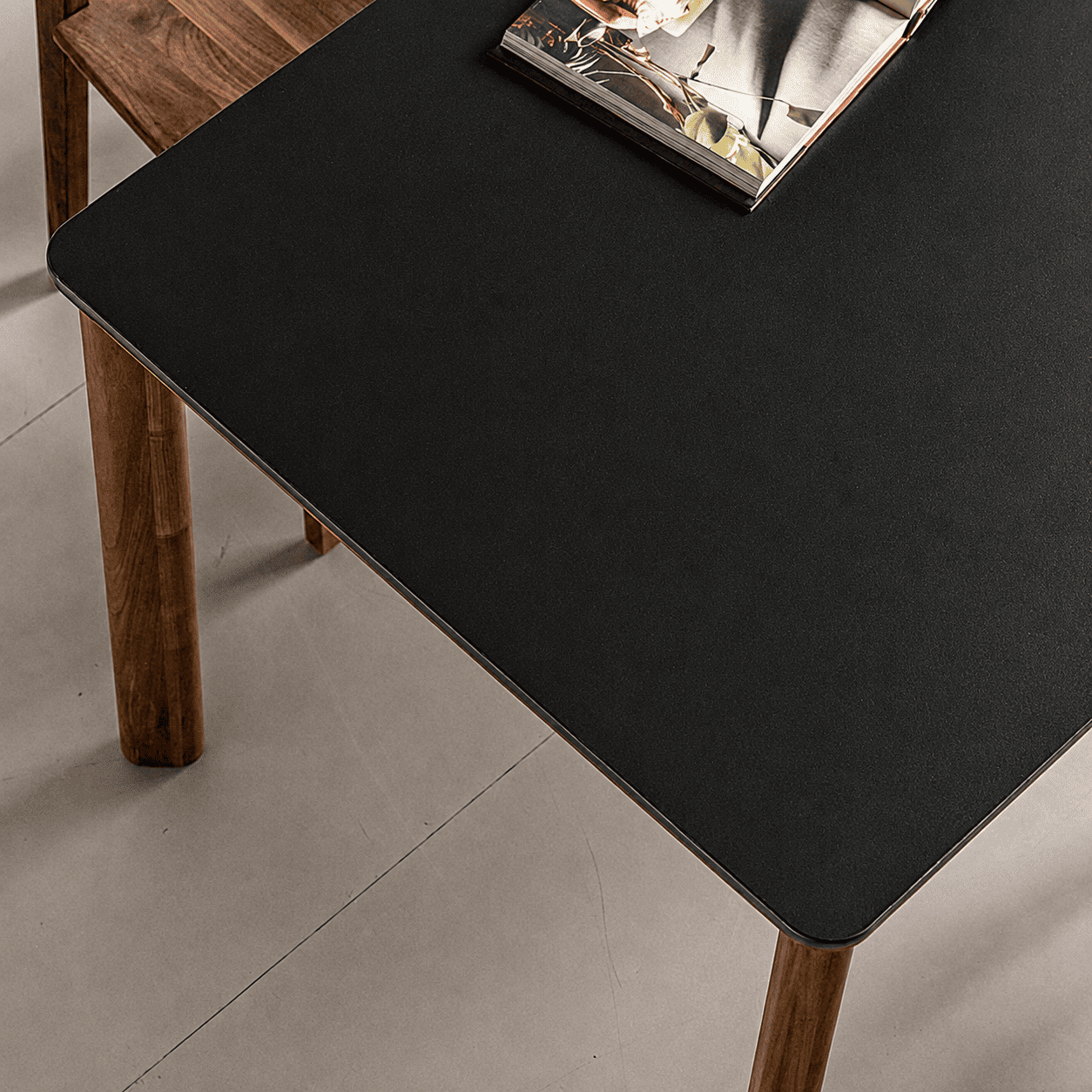 Rectangular walnut dining table with dark ceramic top, rounded edges, and sturdy timber legs