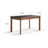 Walnut dining table with ceramic top styled with books, coffee set, and table lamp