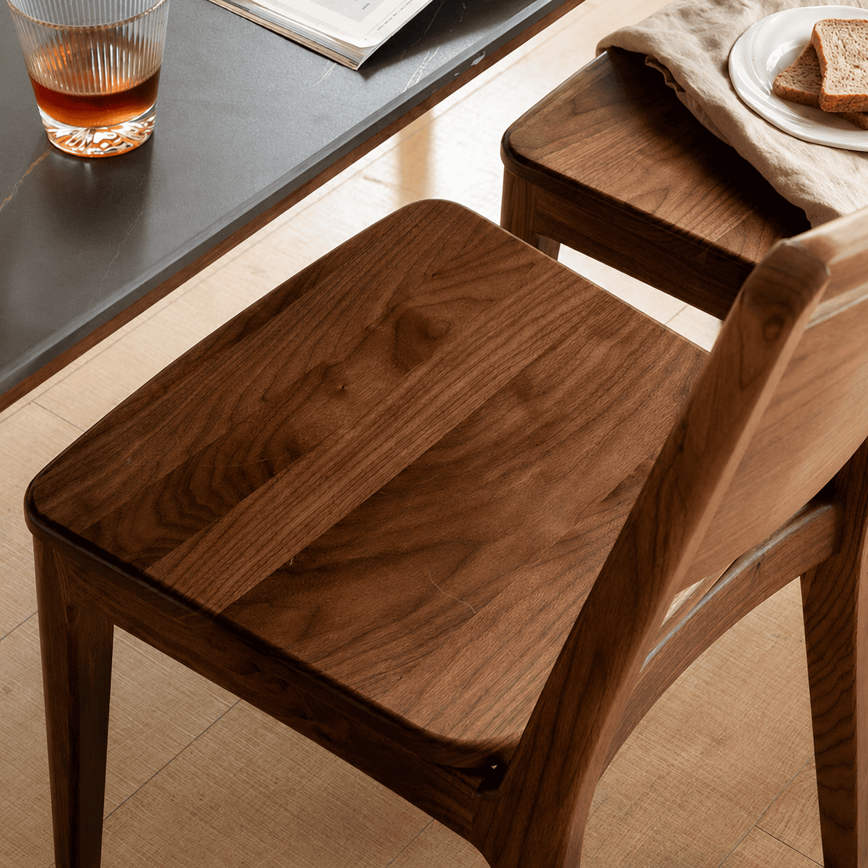 Natural walnut dining chair with tapered legs and minimalist backrest design